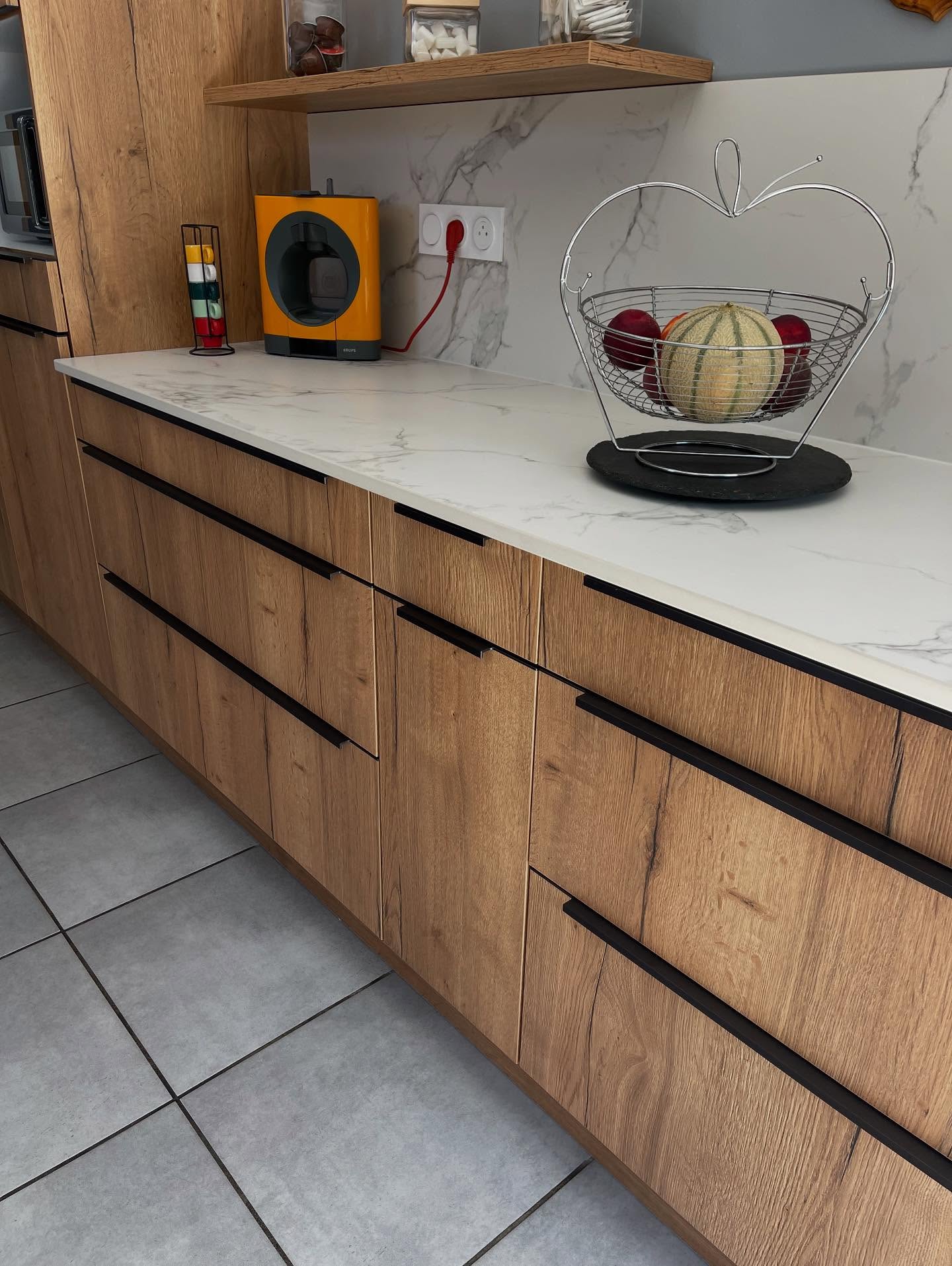 Cette jolie réalisation en Chêne Naturel avec poignée intégrée Graphite brosse, plan de travail et crédences en DEKTON AURA 